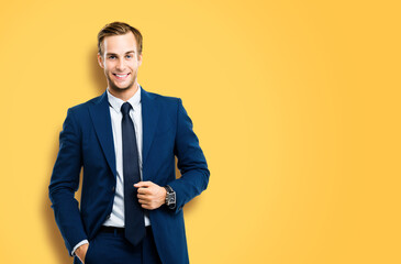 Portrait of happy confident businessman in blue suit and tie, isolated over vivid yellow colour background. Business success concept. Smiling man at studio picture. Copy space for ad text or slogan.