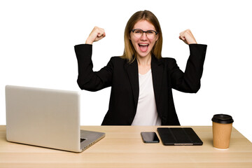 Wall Mural - Young business caucasian woman working on her workplace cutout isolated showing strength gesture with arms, symbol of feminine power