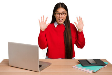 Wall Mural - Young student asian woman in a workplace with a laptop isolated receiving a pleasant surprise, excited and raising hands.