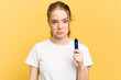 Young cute woman holding a vaper isolated on yellow background shrugs shoulders and open eyes confused.