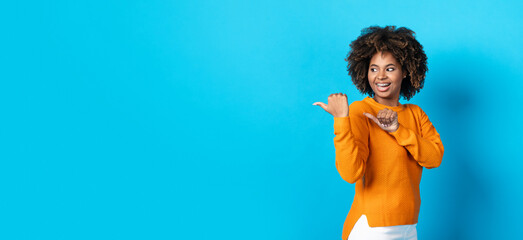 Wall Mural - Cool african american young woman aiming at copy space