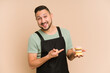 © Asier - Adult latin cook man holding a muffins tray cut out isolated