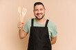 © Asier - Adult latin cook man holding wooden utensils isolated