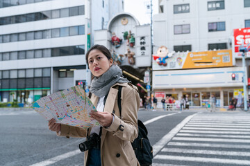 Canvas Print - Asian chinse woman looking at route map while waiting to use crosswalk on the street near Tenjinbashisuji Shopping arcade in Osaka japan