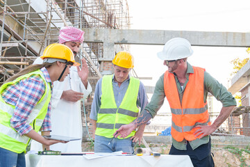 Wall Mural - Diverse team of professionals using tablet computers on construction site. Real estate construction project. with civil engineers, architects, Arabic business investors and explorer with theodolite