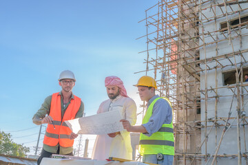 Wall Mural - Diverse team of professionals using tablet computers on construction site. Real estate construction project. with civil engineers, architects, Arabic business investors and explorer with theodolite