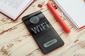 Wall Mural - Opened book, stationery supplies and mobile phone with WiFi symbol on wooden background, closeup