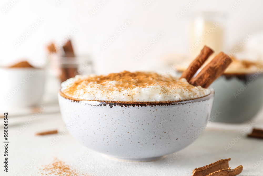 Bowl with delicious rice pudding and cinnamon on white table