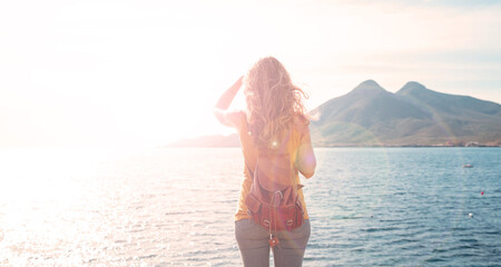 Wall Mural - Woman standing and looking at the sea and sunlight