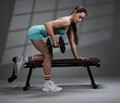 Young woman doing dumbbell row exercise on bench