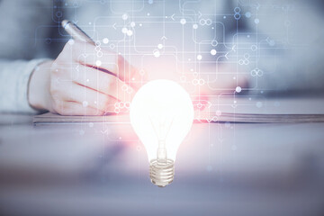 Poster - Bulb hologram over hands taking notes background. Concept of idea. Double exposure