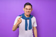 © Bangun Stock Photo - serious angry young Asian man wearing white t-shirt pointing finger at the camera isolated over purple background. people lifestyle concept