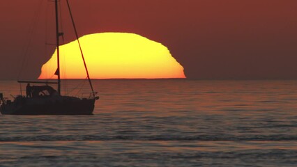Wall Mural - beautiful evening sunset with a big sun and a sailing yacht in the atlantic ocean on the coast of po