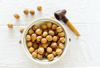 Wall Mural - Closeup of whole walnuts in porcelain bowl and nutcrackeron on a white wooden table. Walnut healthy food .Selective focus.