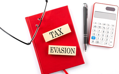 Poster - TAX EVASION text on wooden block on red notebook