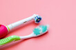 Closeup Old electric toothbrush and normal toothbrush with frayed bristles in close-up view. Expired toothbrush with worn damage brush isolated on pink background. Oral care concept.