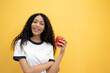 © Chalermphon - Young satisfied happy African American woman 20s in casual look camera hold red bell peppers isolated on plain yellow background studio portrait. People lifestyle food concept