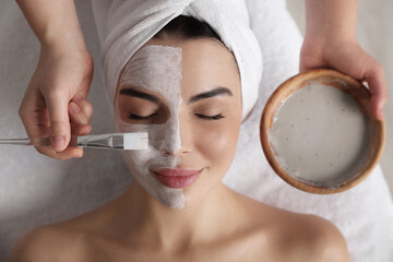 Sticker - Cosmetologist applying mask on woman's face in spa salon, closeup. Top view