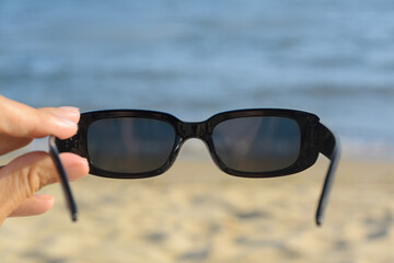 Wall Mural - Woman holding stylish sunglasses near beautiful sea, closeup