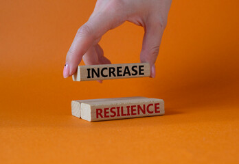 Increase resilience symbol. Wooden blocks with words Increase resilience. Businessman hand. Beautiful orange background. Business and Increase resilience concept. Copy space.