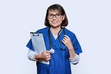 Wall Mural - Portrait of female doctor with clipboard looking at camera on white background