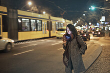Young Woman In The City At Night While Using A Smartphone