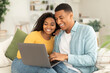 © Prostock-studio - Technology at home. Glad millennial african american wife hugging husband, looking at laptop, have video call