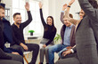 © Studio Romantic - Happy business team having fun in the office. Group of cheerful young people sitting in a circle, giving each other a high five or raising hands up and voting for a good suggestion. Teamwork concept
