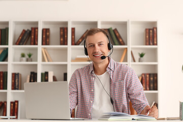 Canvas Print - Young man writing in notebook while studying online at home