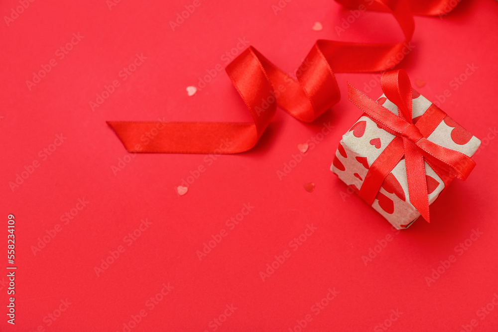 Gift with ribbon and hearts on red background. Valentine's Day celebration