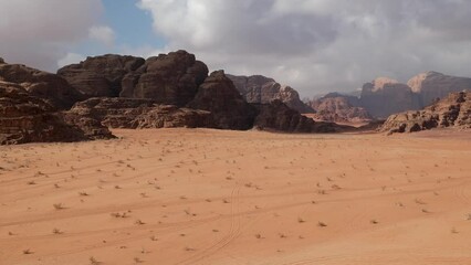 Wall Mural - Panoramic view of Wadi Rum desert in Jordan with clouds moving over flat sand landscape with mountains in background, 