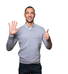 Happy young man doing a number six gesture with his hands