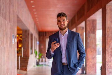 Business or finance corporate man at the entrance of the office with a phone in his hand