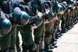 © AndriiKoval - A row of armed special police forces with helmets stands outdoors on the street. Shield. Safety. Conflict. Guard. Assault. Chaos. Protection. Control. Protective. Protected. Guarded. Ready. Safe