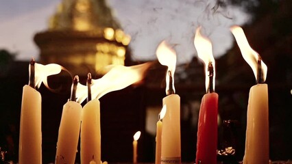 Wall Mural - Slow motion video of candle burning with golden pagoda background.