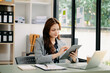 © Nuttapong punna - Beautiful woman typing on tablet and laptop while sitting at the working wooden table modern office..