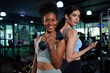 © offsuperphoto - young athletic women smiling and lifting dumbbell in the gym