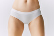 © master1305 - Cropped image of female body, belly, buttocks in underwear posing over grey studio background. Front view