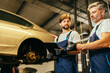 © Iryna - Two car mechanic diagnosing vehicle at the auto service. Car service, repair, maintenance and people concept.