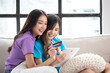 Happy young asian lesbian couple shopping online while relaxing together in the morning at home. Lesbian couple together concept.