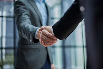 Two diverse professional business men executive leaders shaking hands at office meeting