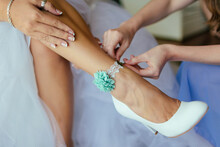 Close-up Photo The Bridesmaids Are Helping To Put On White High Heels And A Blue-green Floral Anklet For Her. She Wore A Silver Ring And A Bracelet. To Wait To Attend The Wedding Ceremony.