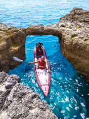 Isola di Paxos, ragazza in kayak tra le scogliere e le grotte marine