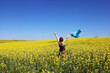 © Cavan Images - A woman in a field with yellow flowers on a blue sky background