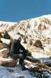 © Jordi - Adult male model hiking in mountains full of snow in a sunny day. He takes a break and sits down.