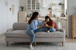 © DimaBerlin - Loving mother sitting with sad daughter on sofa at home, helping child to cope with friendship breakup. Disappointed teen girl looking at phone screen, sharing feelings with mom. First love concept