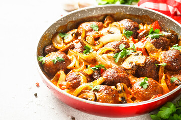 Sticker - Meatballs with champignon and vegetables stewed in tomato sauce in a frying pan. Top view with copy space at light stone table.