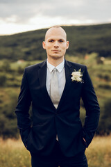 Wall Mural - the groom during a wedding photo shoot in the middle of nature, a stylish man in a jacket