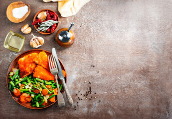 Canvas Print - Closeup of fried fish with green beans on plate on dark background