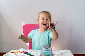 а little girl paints an ice castle with colored paints and she is very happy with the process of painting a girl in a blue t-shirt with the inscription 